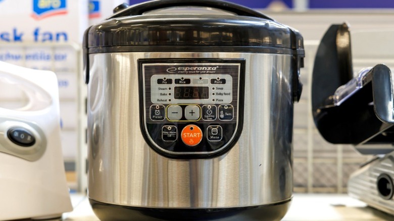 A stainless steel multicooker on a store shelf.