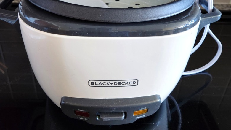 A white Black+Decker rice cooker on a black counter.