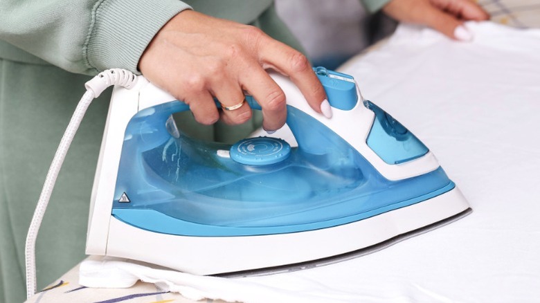 A steam iron on a black background with visible steam coming out of the iron.
