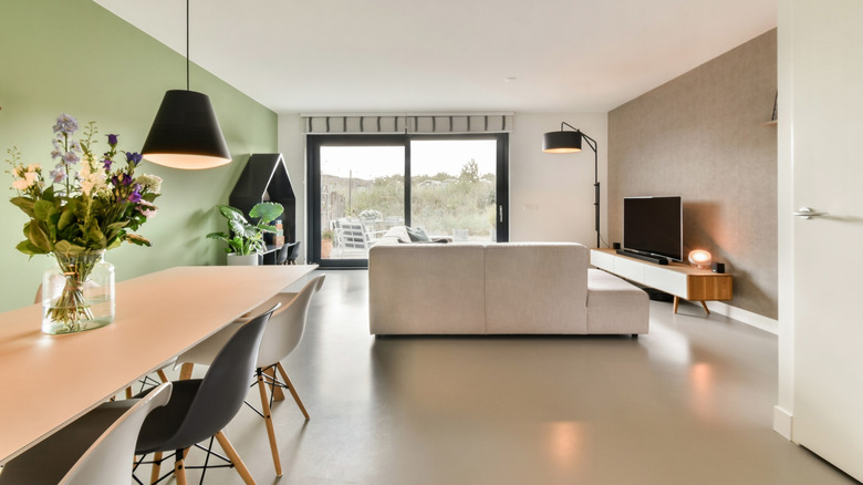 An open-plan dining room and living room with pastel furniture and walls.
