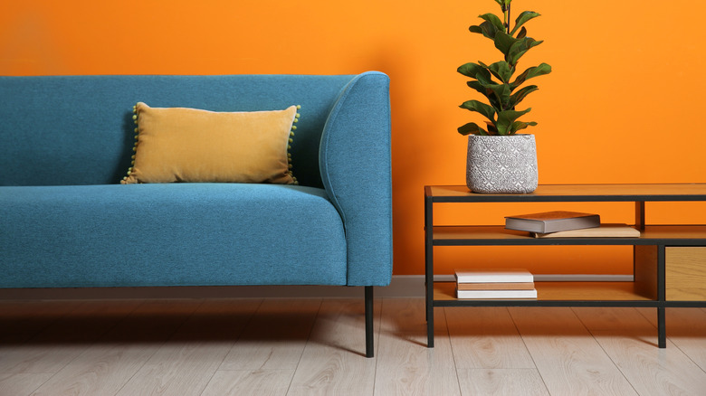 A blue sofa against a bright orange wall.