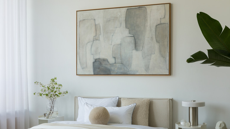 A large abstract painting on the wall above a bed.