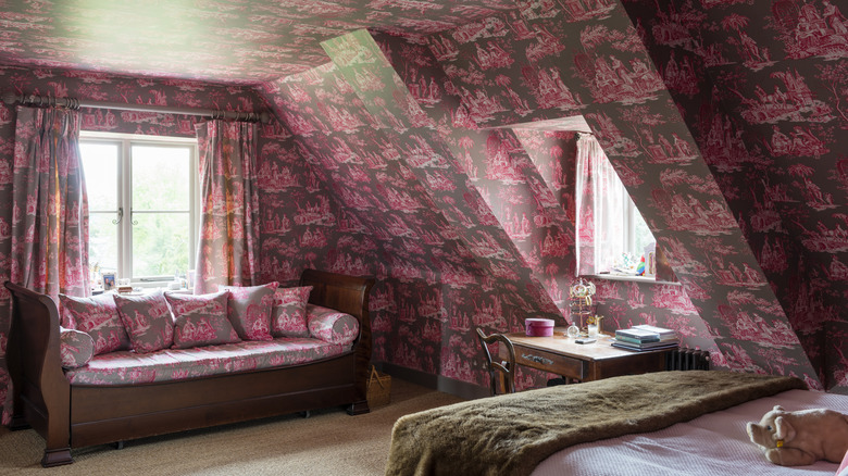 Matching black and pink wallpaper, curtains and sofa in the same fabric in an eaves bedroom.