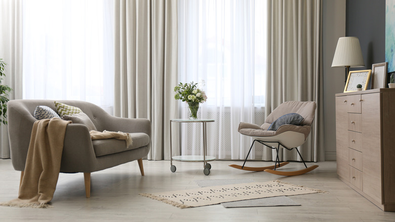 A living room with tonally matching gray sofa, light gray curtains, and darker gray walls.