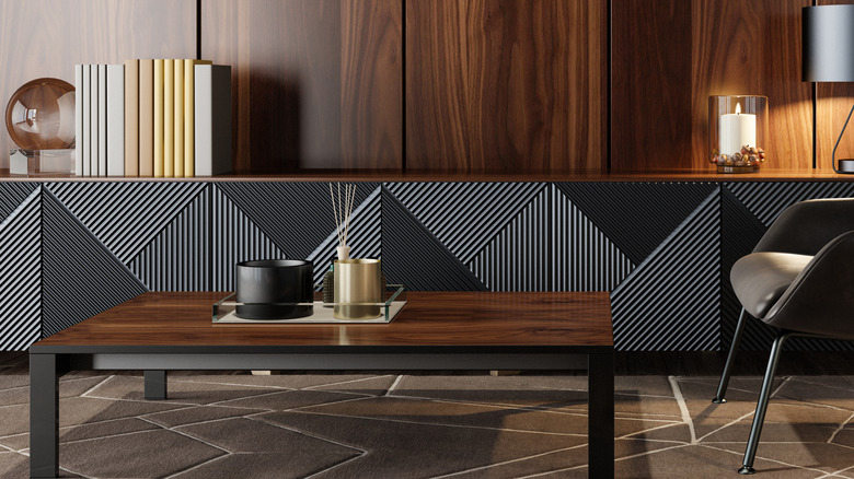 A dark panelled wood wall with black and grey textured sideboard and wood coffee table in front.