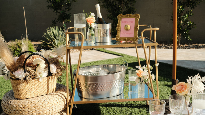 A bar car set up with antique glass and metallic bar cart for a bridal party.