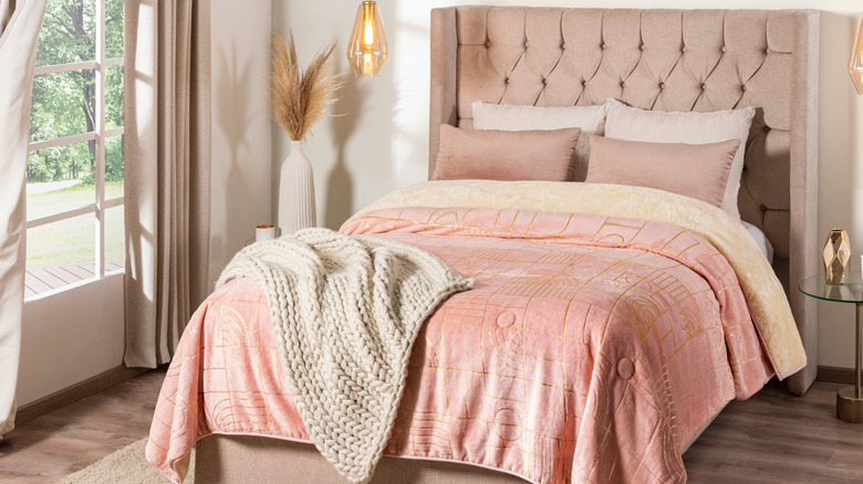 A bedroom with a bed outfitted in a salmon pink duvet and a tufted headboard.