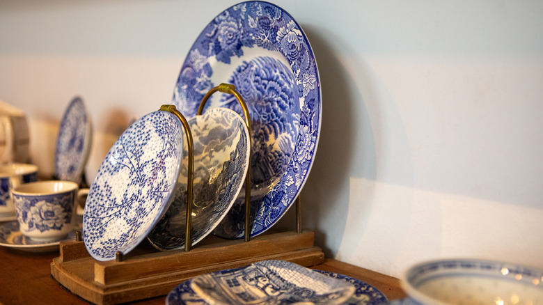 A series of decorative plates and china sitting on a shelf on display.
