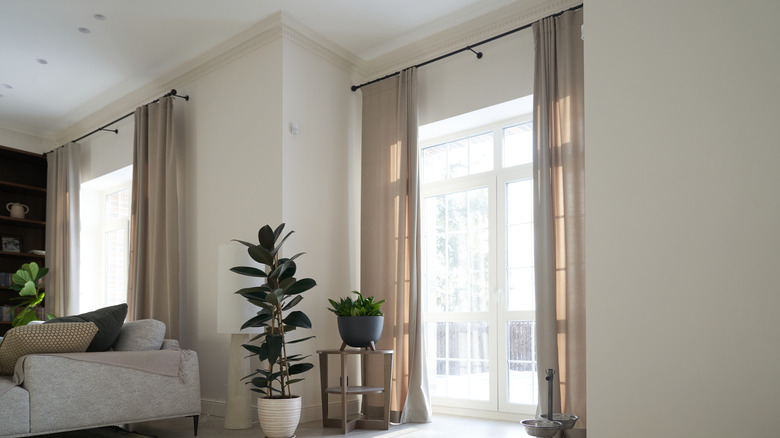A living room with taupe linen curtains hung on black metal rods.