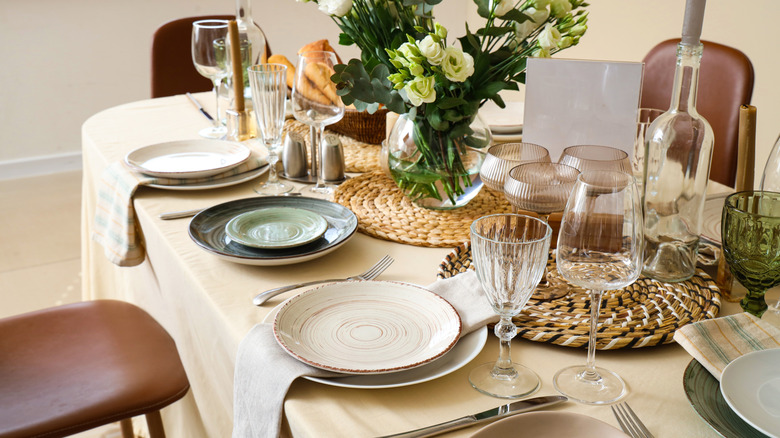 A table set with a neutral table cloth, wicker accents, and stoneware.