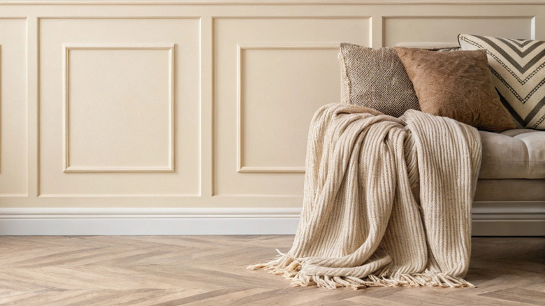 An elegant living room with organic decor, including a textured couch and a throw pillows and blankets.