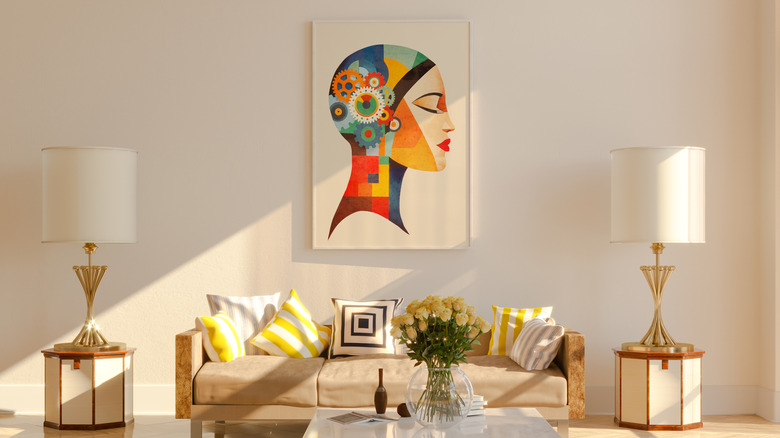 A living room with a brightly designed piece of wall art on a neutral white all.