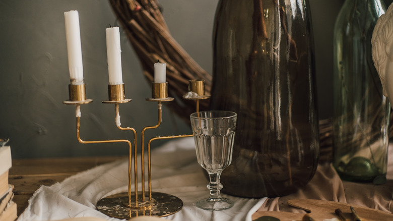 A brass candlestick on table with white candlesticks.