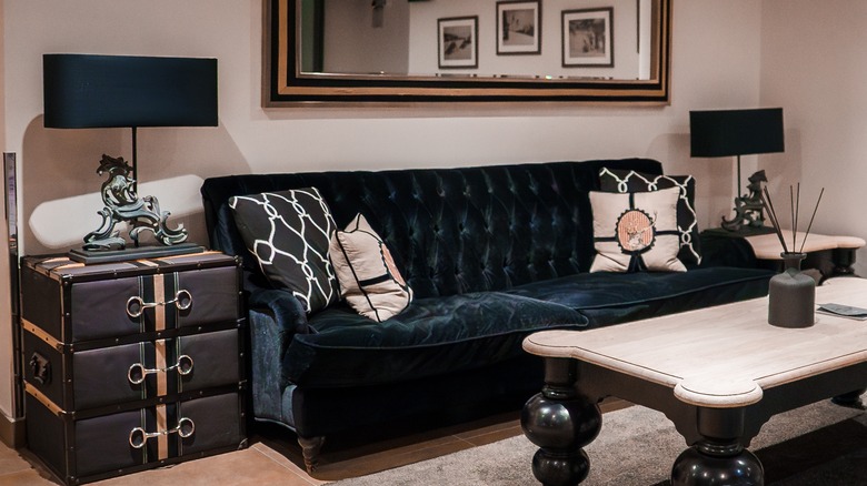 A living room with a blue couch and horse lamps.