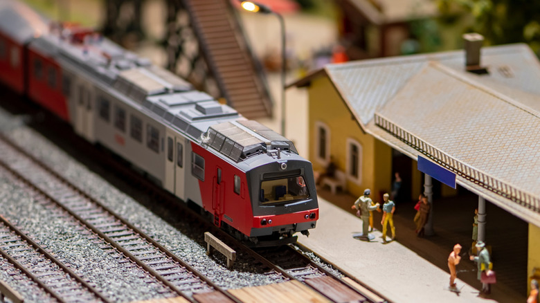 A red and gray model train with toy figurines.