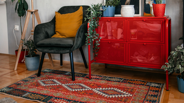 Oriental rug under a black chair and red furniture piece.
