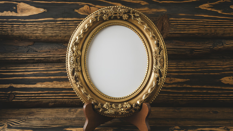 A vintage gold picture frame on wood stand.