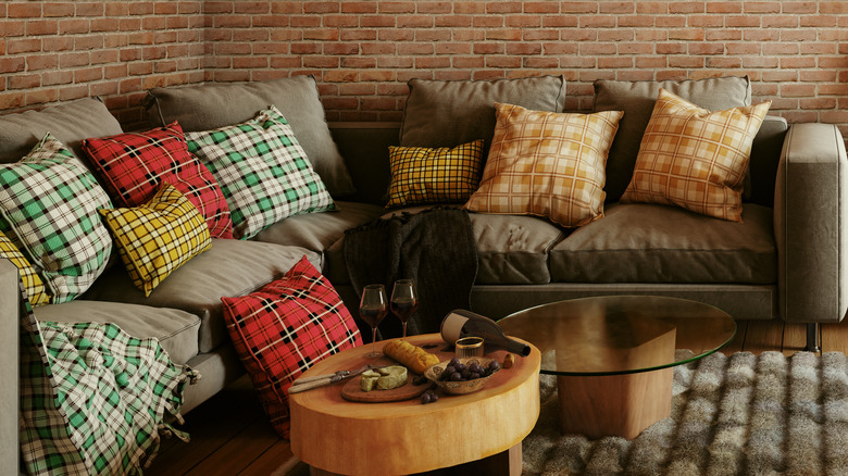 Plaid pillows on a gray couch next to coffee tables.