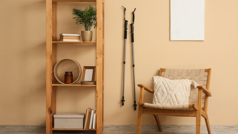 Ski poles against a wall next to a shelf and chair.