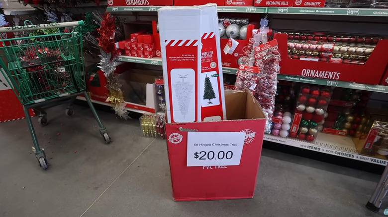 The Dollar Tree 6 ft Christmas tree in boxes inside a store.