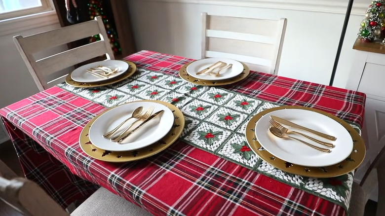 A tablescape with the gold cut out plates from Dollar Tree underneath white plates and gold cutlery.