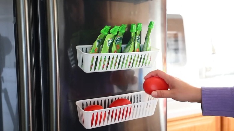 Person putting a tomato in a DIY magnetic rack on the side of refrigerator