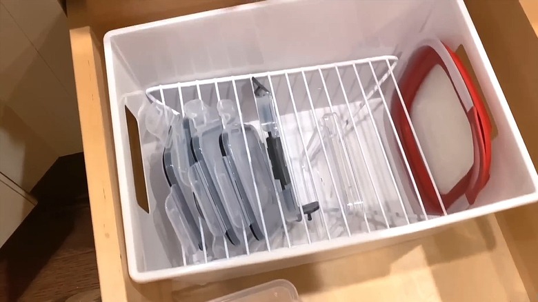 White plastic bin with Dollar Tree wire cabinet shelf inside holding storage container lids