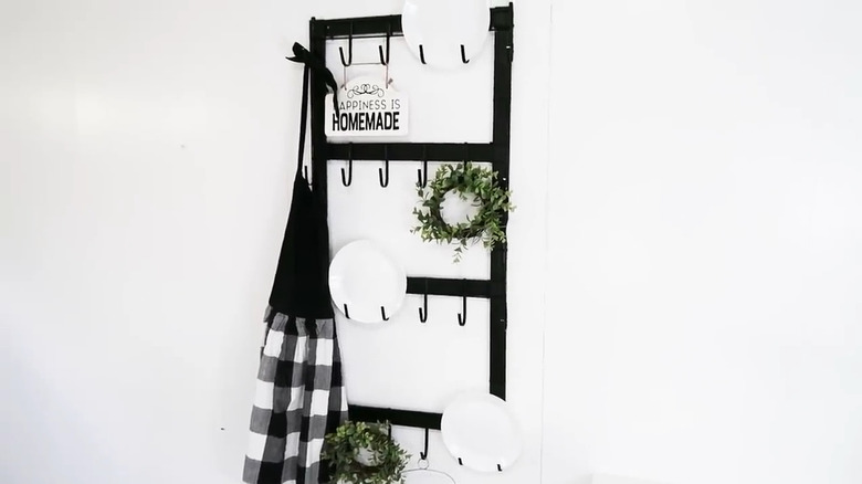 Black DIY wall rack with four rows of hooks attached to a wooden frame