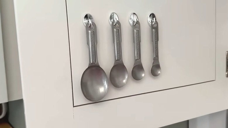 Dollar Tree hooks on cabinet door holding measuring spoons