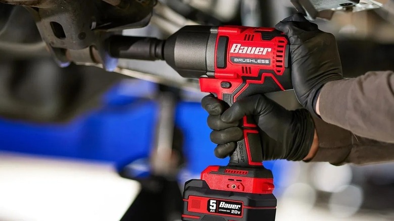 Person using a high-impact wrench on a vehicle's undercarriage
