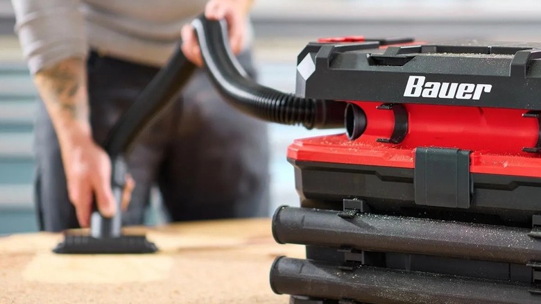 Person vacuuming sawdust on a workbench