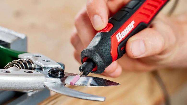 Person using a rotary tool to sharpen pruners