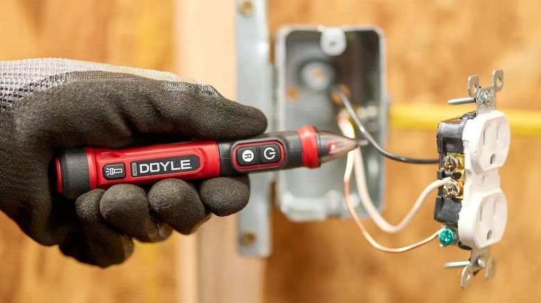 Person using a voltage tester on a power outlet wire