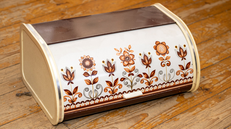 A vintage metal bread box on a wooden table.