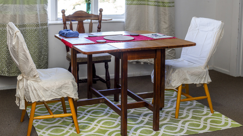 A drop-leaf table with cloth-covered chairs in a kitchen.