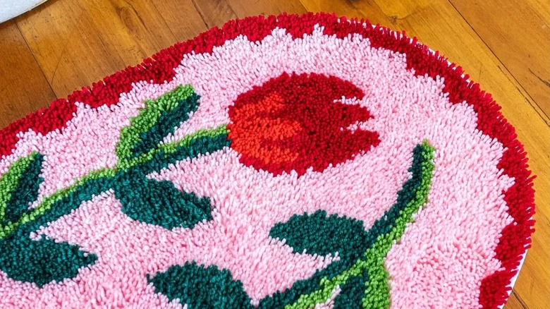 A latch-hook rug with a tulip pattern adorns on a wooden floor.