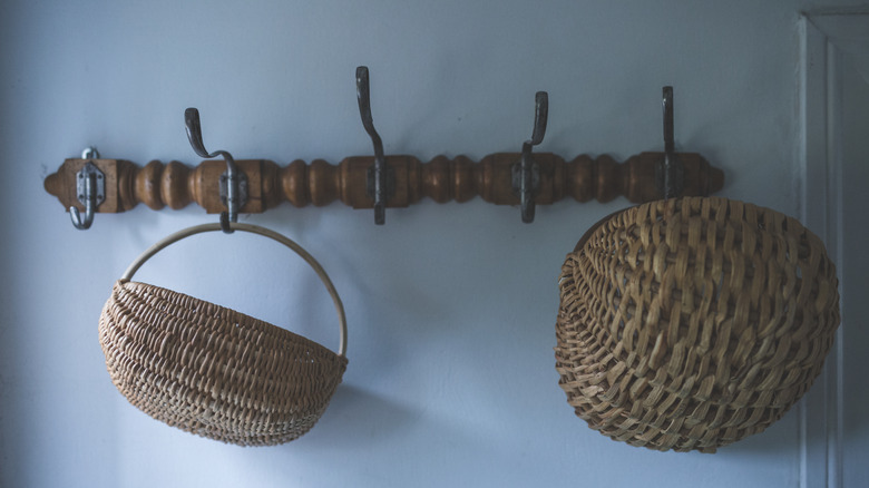 Wicker baskets hanging on a wooden coat rack.
