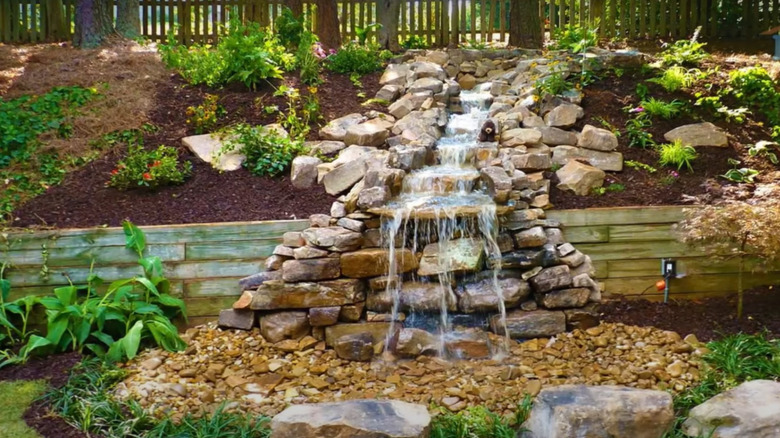 a water feature built into a sloped yard made from natural stones