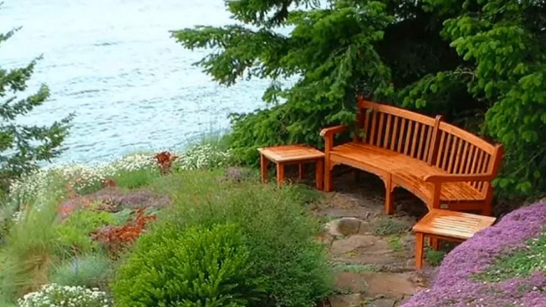 a wooden bench and side tables in a sheltered spot, overlooking a seaview