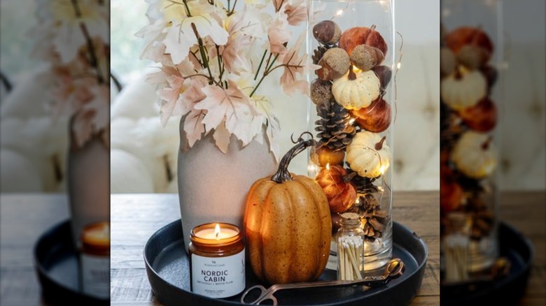 Vase of pinecones and mini pumpkins arranged with fairy lights