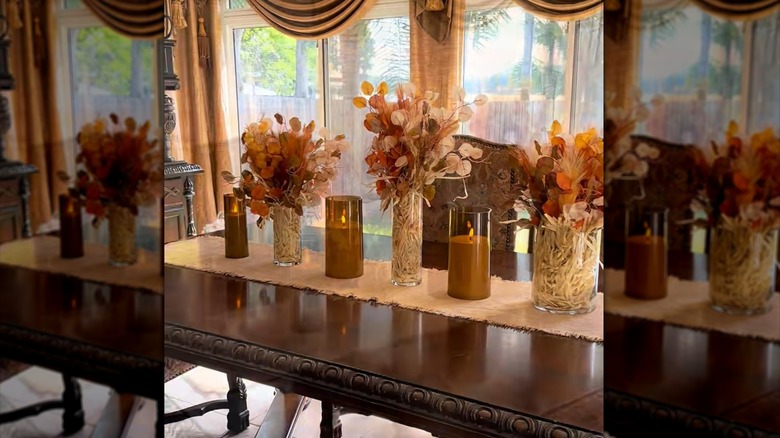 Elegant table runner covered with tall vases of flowers and candles