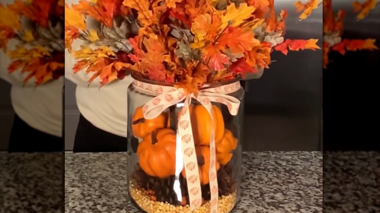 Large jar of mini pumpkins and dried kernels made into a centerpiece