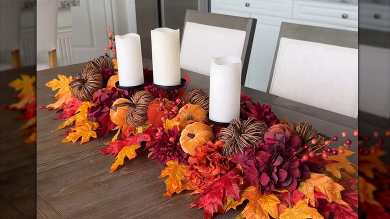 Floral centerpiece made of mini pumpkins, candle holder, and a pool noodle
