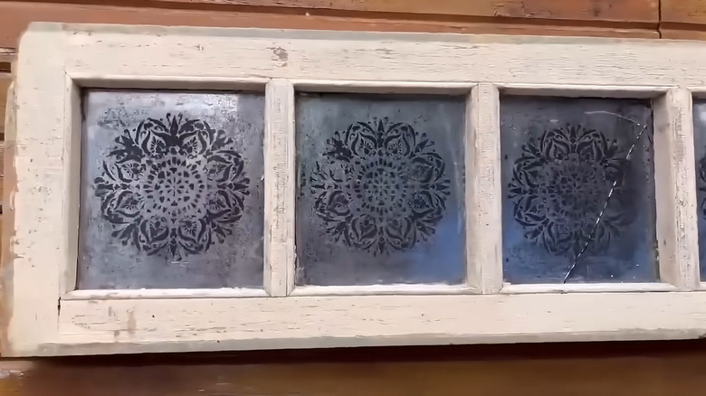 an old window frame has been stenciled and painted with mirror paint