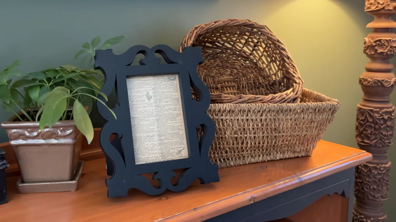 framed dictionary page on a shelf with baskets and plants