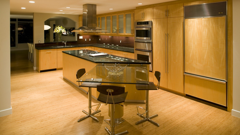 A contemporary, wooden kitchen with white oak-style cabinets and bamboo flooring.