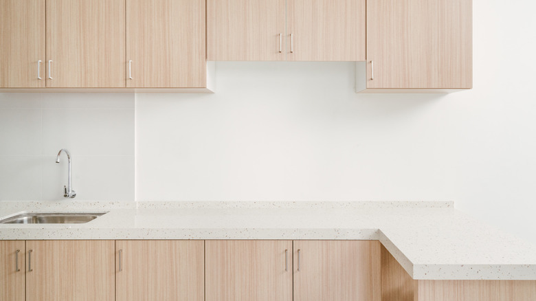 An ultra-contemporary kitchen with blonde, white oak slab cabinets and a quartz countertop.