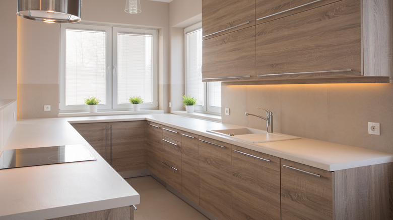 A modern kitchen with white upper cabinets and light white oak lower cabinets paired with a honey oak floor.