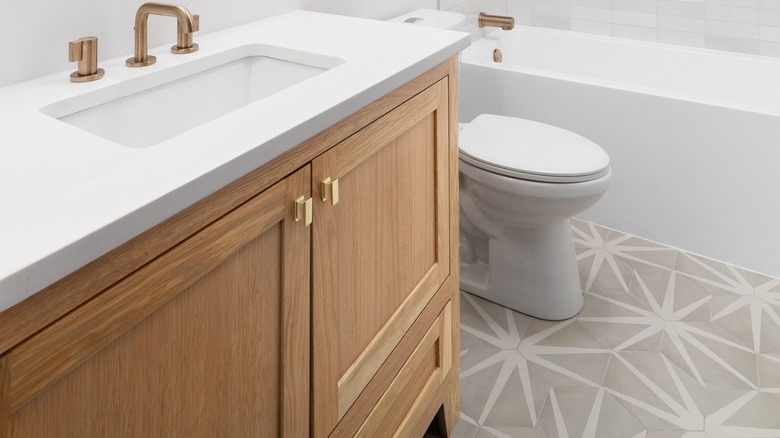 A close up of a white oak cabinet bathroom vanity, toilet, and a printed star tile.
