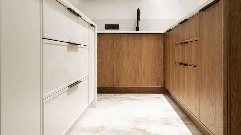 A kitchen with stained, white oak cabinets and light sandstone tile floors.